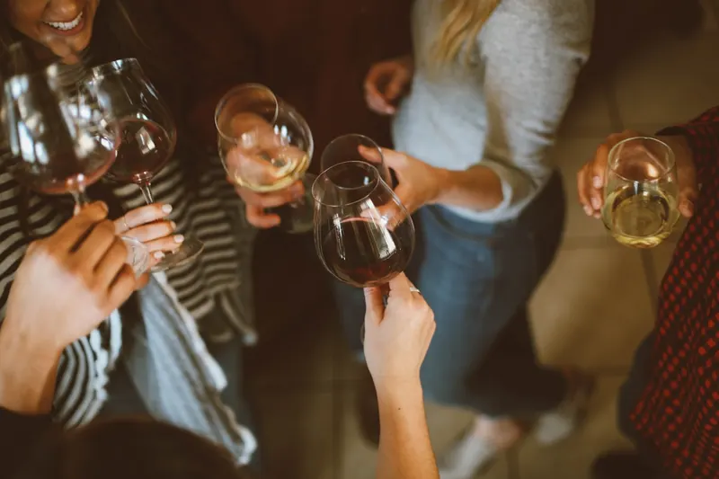 Convives trinquant avec des verres de vin autour d’une table